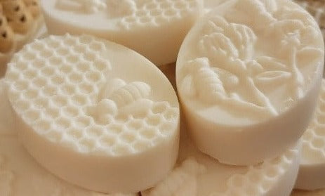 Oval bars of soap molded with honeycomb, bee, and flower patterns on top.